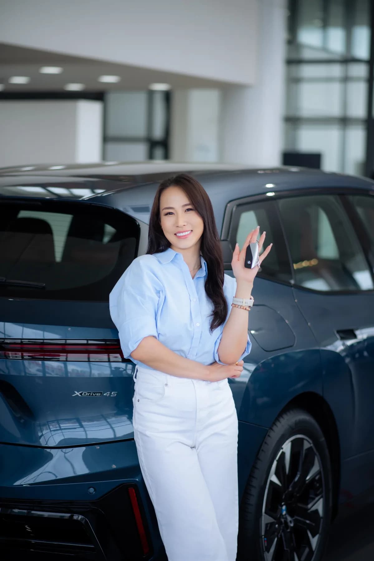 Driver holding the keys to her new vehicle in a showroom